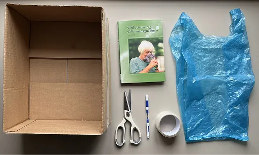 En kartong, sax, penna, tejp, bok och plastpåse.